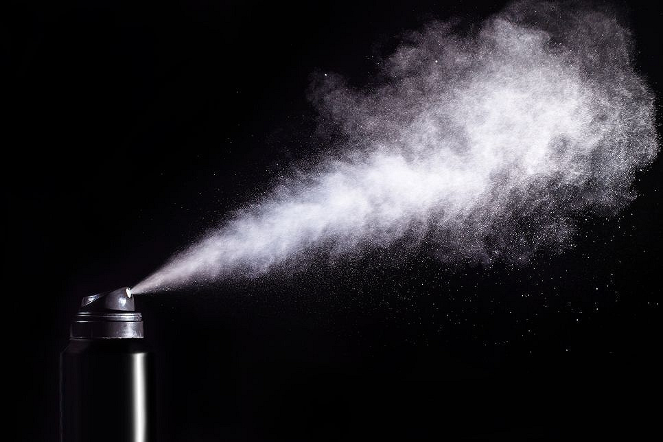 Zdjęcie przedstawia rozpylany gaz pieprzowy w chmurze na czarnym tle.