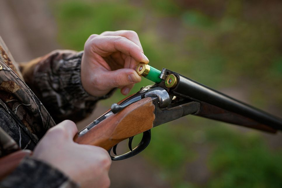 Zdjęcie przedstawia mężczyznę ładującego wiatr&oacute;wkę nabojami.